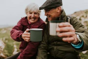 Happy senior couple drinking from mug, outdoor camping
