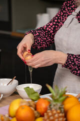 A chef demonstrates the precise art of egg separation, focusing on the egg yolk and white over a bowl, essential for baking recipes.