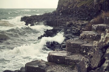 Hexagonal basalt columns of the Giant's Causeway in Ireland. The moody atmosphere and splashing waves highlight the rugged beauty and geological wonder of this famous coastline.