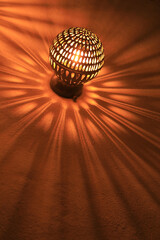 lámpara de pared metálica imitando a un sol haciendo sombras en forma de rayos y fuego...
