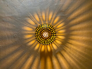 lámpara de pared metálica imitando a un sol haciendo sombras en forma de rayos y fuego...