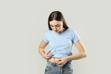 Diabetes. Woman making insulin injection into her belly on grey background