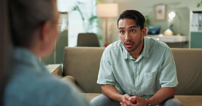 Therapy, talking and man with psychologist in office for mental health, anxiety or depression. Upset, mad and male person with emotions speaking to healthcare worker for psychiatry advice in clinic.