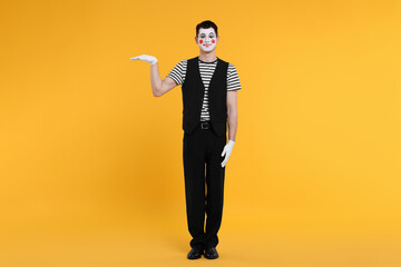 Funny mime artist posing on orange background