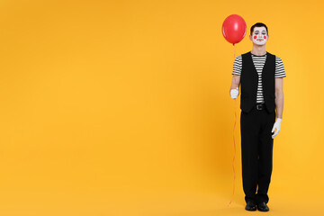 Funny mime artist with balloon on orange background. Space for text