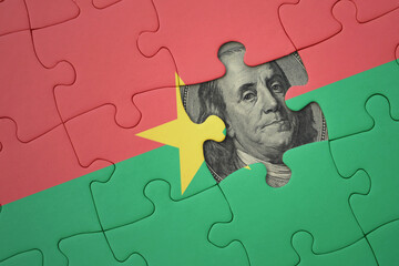 puzzle with the national flag of burkina faso and usa dollar banknote. finance concept