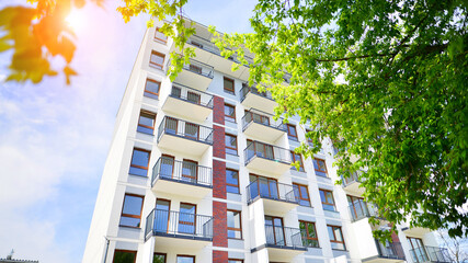 Modern residential building with new apartments in a green residential area. Eco architecture. Green tree and new apartment building. The harmony of nature and modernity.