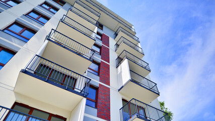 A view at a detail of a modern white apartment building with blue sky background.