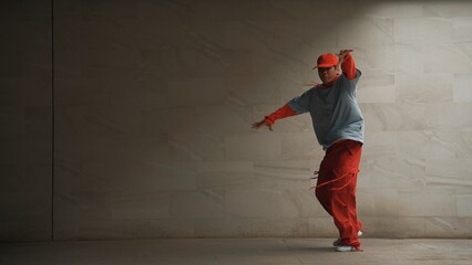 Handsome choreographer practice street dance in gray background. Young attractive b boy dancer...