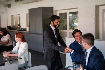 Group of workers in the rest area greeting the disabled colleague in a wheelchair. Concept: business