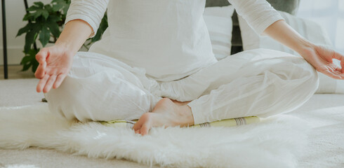 a woman wearing white clothes sitting in easy cross meditating, doing yoga at home, calm meditation, zin
