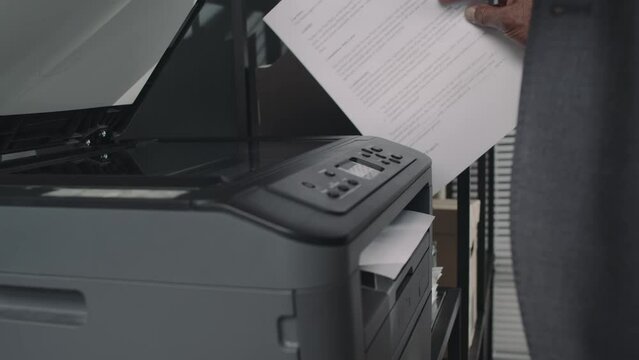 Side midsection footage of unrecognizable employee making scan or copy of documents using all in one printer in modern office