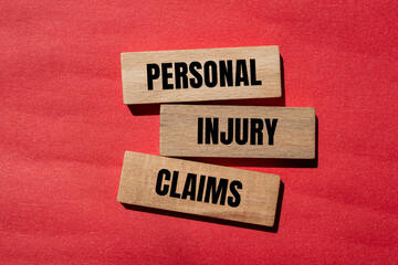 Personal injury claims written on wooden blocks with red background. Conceptual personal injury...