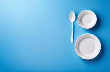 Disposable white biodegradable tableware on a light background