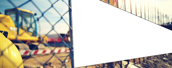 Tractor parked adjacent to fencing mesh on construction site. Blank board poised for future ads blending industrial might with marketing potential.