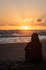 Woman on the beach contemplating the sunrise