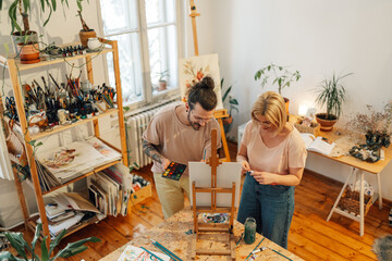 Top view of artistic couple painting together at creative atelier on easel