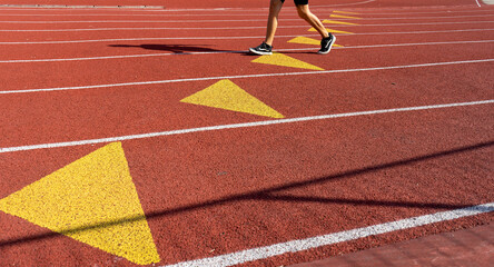 Partial view of an athlete running on a lane of the athletics track at an outdoor sports center in Paris on a sunny day