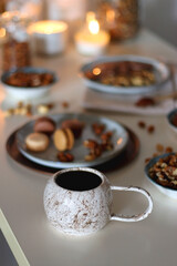 Cup of tea or coffee, cookies, macaroons, chocolate, various nuts and cocoa powder on white background. Selective focus.
