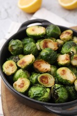 Delicious roasted Brussels sprouts in baking dish on table, closeup