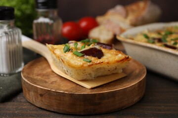 Spatula with piece of tasty sausage casserole on wooden table, closeup