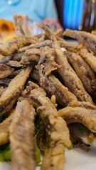 Appetizing fried anchovies on a green salad leaf, close-up