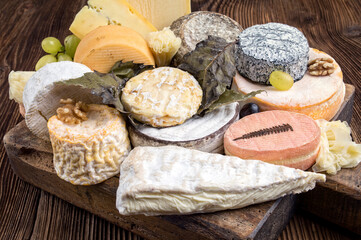 Traditional cheese platter with soft cheese and fruits served as close-up on a rustic wooden design board