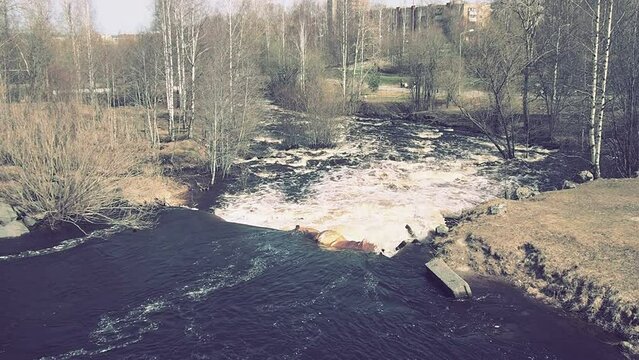 Spring flood. Rushing water in the river, top view. Dark ferrous water rushes in the stream. A yellow-white foam. Karelia, Lososinka River in spring. Floods, tsunami and climate change. Water movement