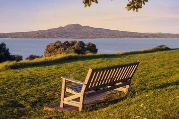 Naklejka na ściany i meble Park Bench on North head at sunset. Rangitoto Island is in the background. Devonport, Auckland, New Zealand.