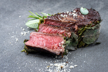 Traditional barbecue dry aged rib-eye beef steak coated with sage leaves and served as close-up on...