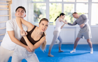 Sportive young woman practitioner of self-defense courses applying attack methods on young man