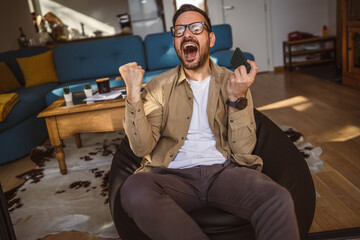 Adult man with eyeglasses play video games on his phone at home