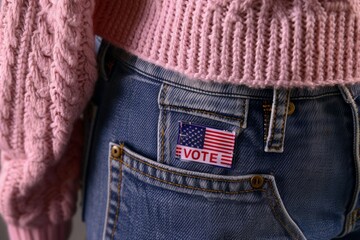 close up of a person in jeans and pink sweater, there is an american flag and the word "vote" on the back of the jeans. Presidential elections 2024 concept