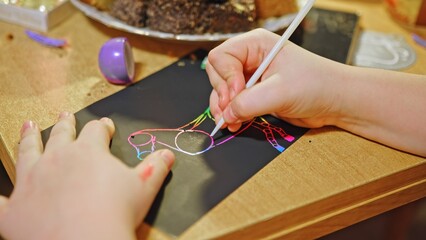 Young Smart Creative Caucasian Girl Having Fun Creating Art Playing with Colorful Scratch Pad...