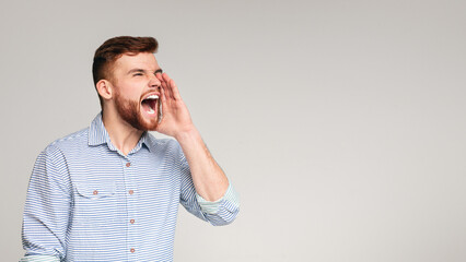 Shouting guy. Crazy emotional man screaming over grey background, panorama, free space