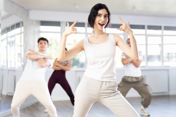 Expressive young brunette honing hip-hop dance moves in mirrored choreographic studio setting...