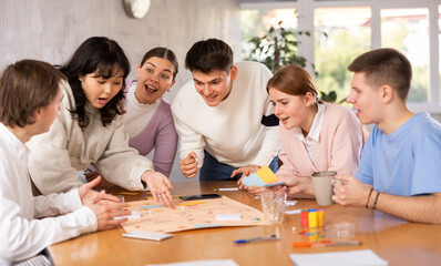 Group of happy young people playing board game