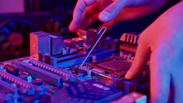Technician laying CPU into the motherboard socket Computer service and upgrade concept. Processor close up in neon light