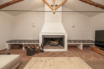 A large fireplace of a house with a basket full of logs and work benches on the wall