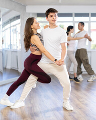 Young people learning tango dance at lessons in dance studio
