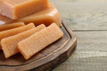 Tasty sweet quince paste on wooden table, closeup. Space for text