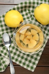 Delicious quince drink in glass bowl, fresh fruits and spoon on wooden table, top view