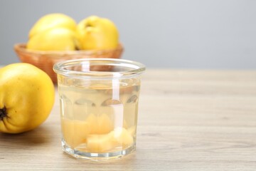 Delicious quince drink in glass and fresh fruits on wooden table, space for text