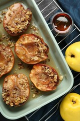 Tasty baked quinces with nuts and honey in dish on table, flat lay