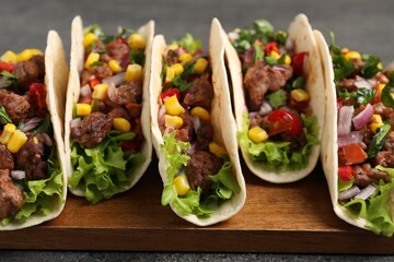 Delicious tacos with meat and vegetables on table, closeup