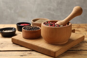 Different sorts of aromatic pepper on wooden table
