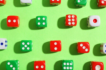 Many color game dices on green background, flat lay