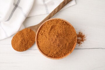 Aromatic spice. Ground red pepper in bowl and spoon on white wooden table, top view