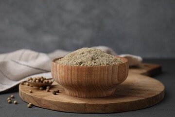 Aromatic spice. Ground pepper in bowl and peppercorns on grey wooden table, closeup