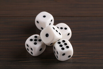 Many white game dices on wooden table, closeup